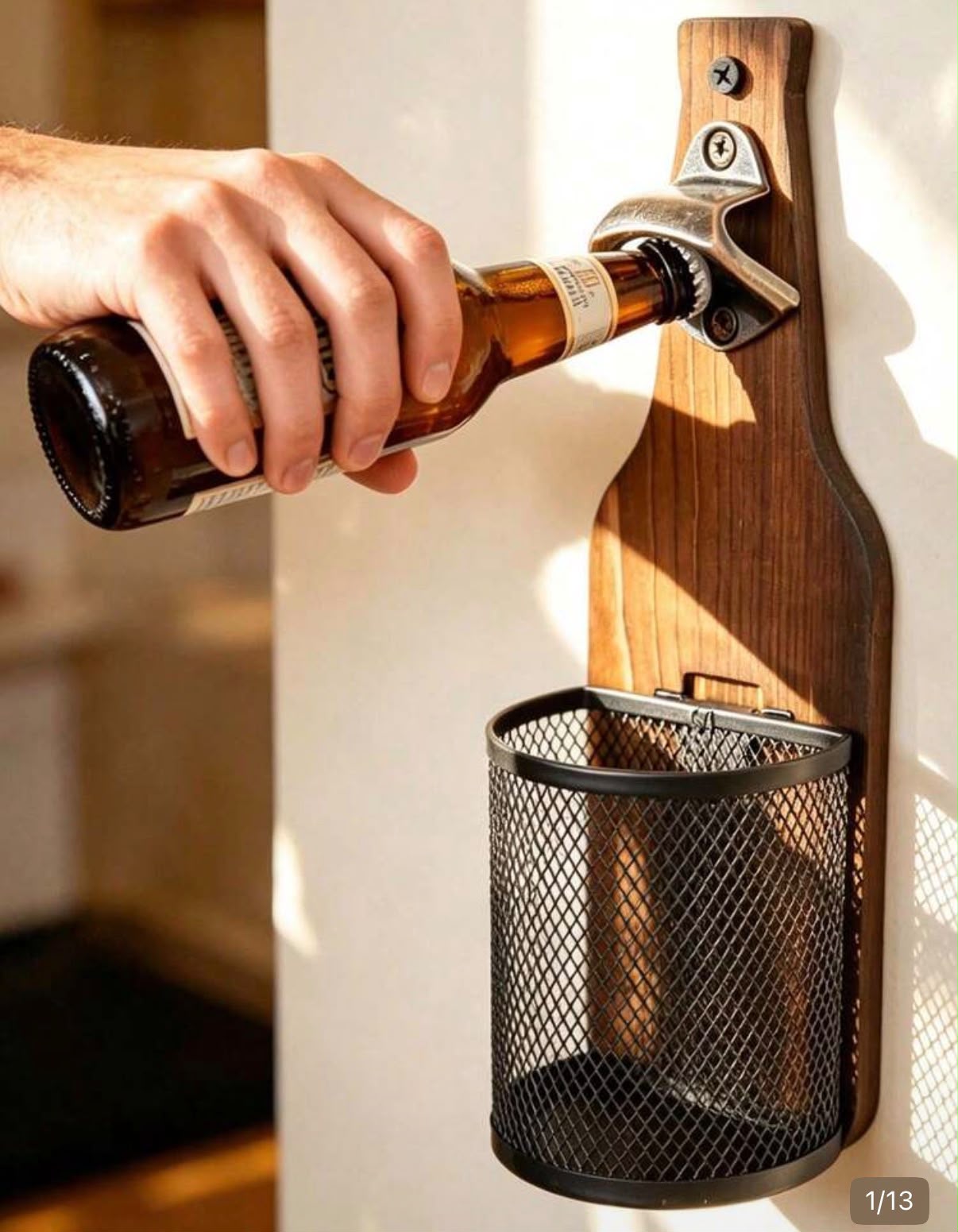 A hand opening a beer bottle on the Doppie wooden wall-mounted opener, with the cap basket underneath